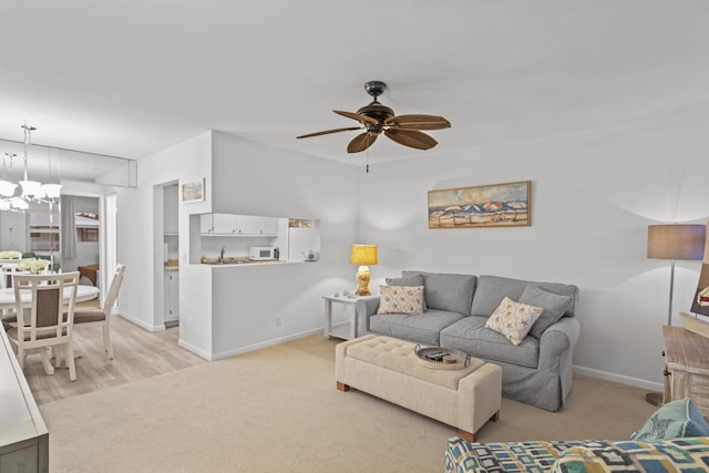 living room with ceiling fan with notable chandelier and light carpet