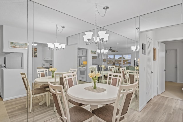 dining room with ceiling fan with notable chandelier and light wood-type flooring