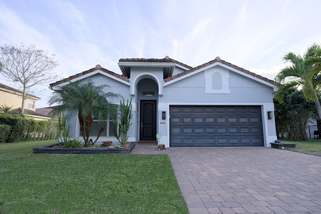 mediterranean / spanish house featuring a garage and a front yard