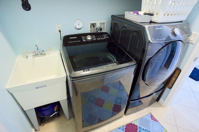 washroom with sink, separate washer and dryer, and light tile patterned flooring