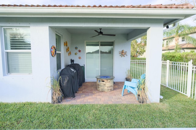 doorway to property featuring ceiling fan, a patio area, and a lawn