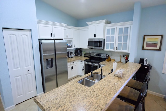 kitchen featuring white cabinets, appliances with stainless steel finishes, a breakfast bar, and sink