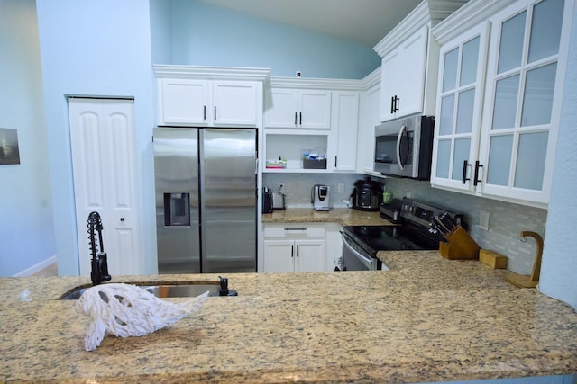 kitchen with sink, white cabinetry, stainless steel appliances, and vaulted ceiling