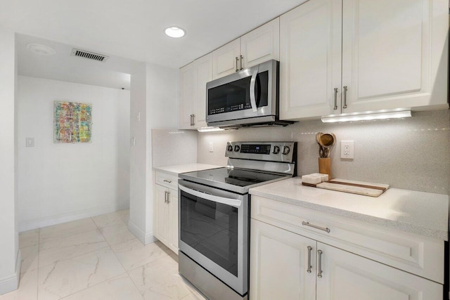 kitchen featuring tasteful backsplash, white cabinets, and appliances with stainless steel finishes