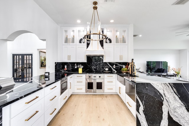 kitchen with decorative light fixtures, white cabinetry, and dark stone counters