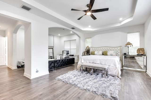 bedroom featuring hardwood / wood-style floors, a tray ceiling, and ceiling fan