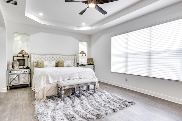 bedroom featuring a tray ceiling, ceiling fan, and hardwood / wood-style floors