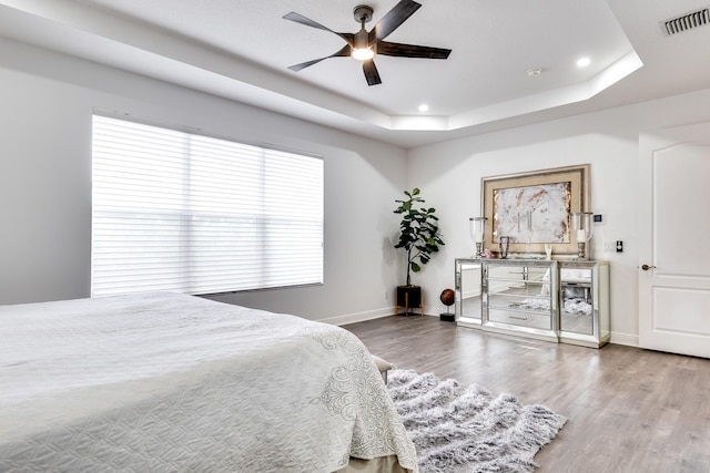 bedroom with a raised ceiling, ceiling fan, and hardwood / wood-style flooring