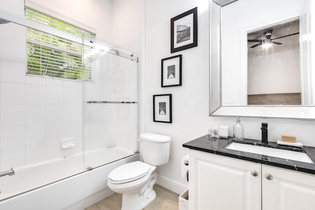 full bathroom with ceiling fan, hardwood / wood-style floors, toilet, shower / bath combination with glass door, and vanity