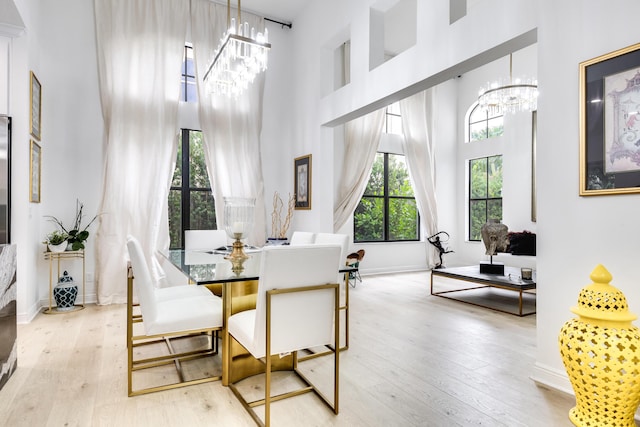 dining area with a high ceiling, light hardwood / wood-style flooring, and an inviting chandelier