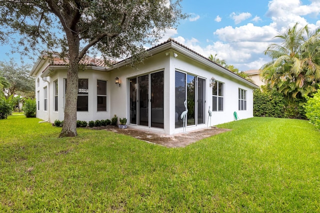 rear view of property with a yard and a sunroom