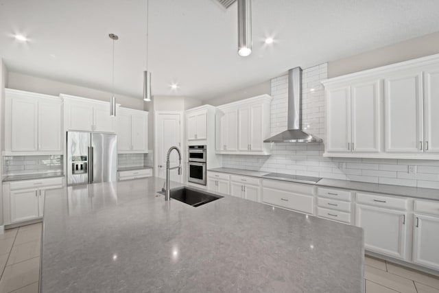 kitchen with wall chimney exhaust hood, stainless steel appliances, stone counters, white cabinetry, and hanging light fixtures