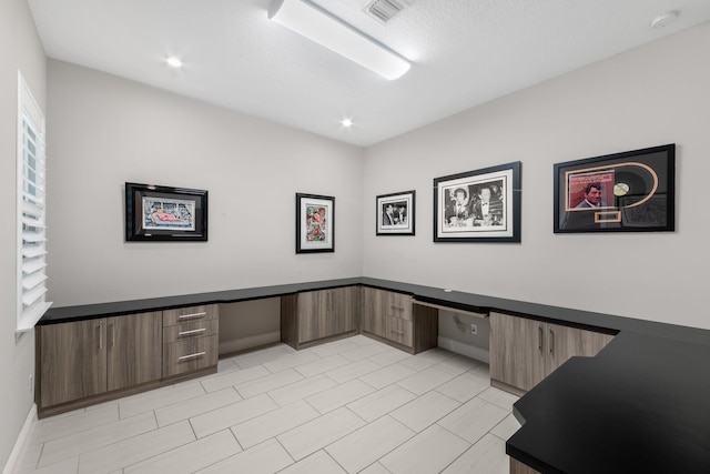 home office featuring built in desk and a textured ceiling