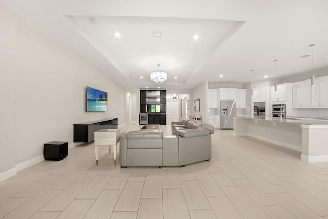 living room with a raised ceiling and a notable chandelier