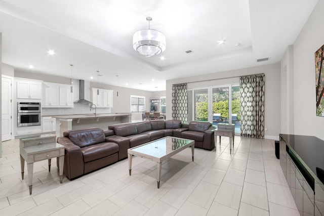 living room with light tile patterned floors, a tray ceiling, and sink