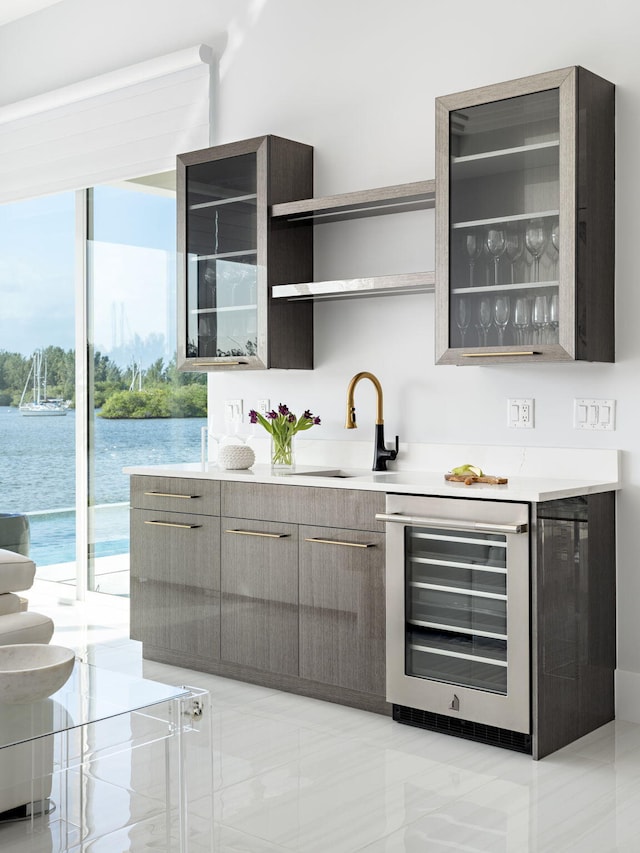 bar featuring sink, a water view, and beverage cooler