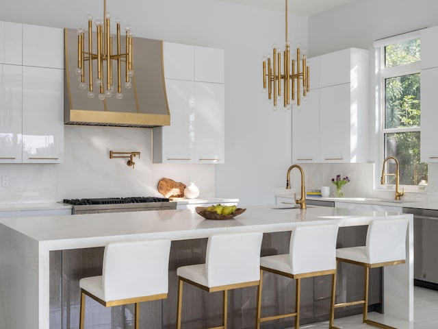 kitchen with white cabinets, a breakfast bar, backsplash, and an island with sink