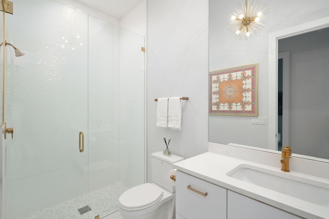 bathroom featuring vanity, toilet, a shower with shower door, and an inviting chandelier