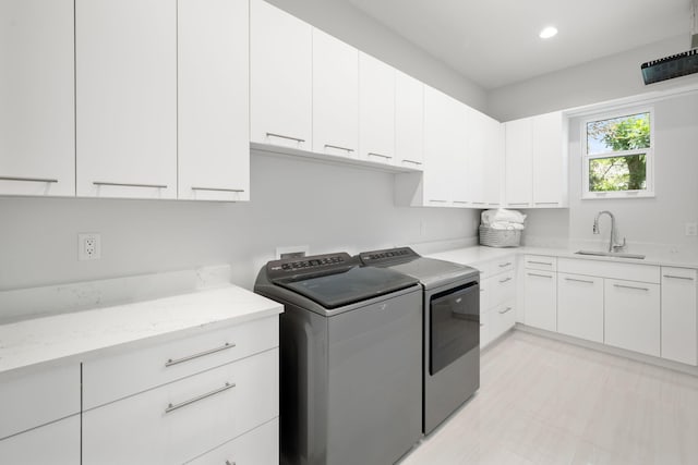 laundry area featuring washing machine and dryer, sink, and cabinets