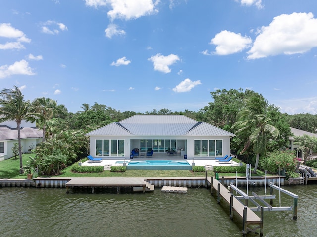 back of property with a water view and a patio