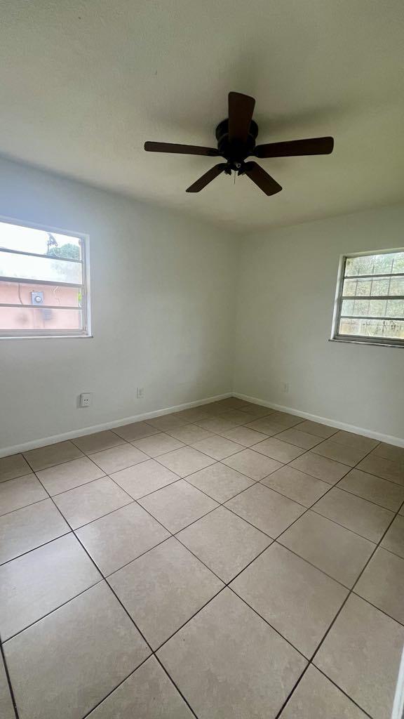 spare room with ceiling fan and light tile patterned floors