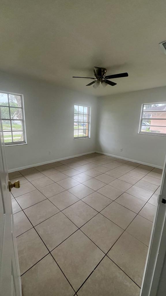 empty room with light tile patterned floors and ceiling fan