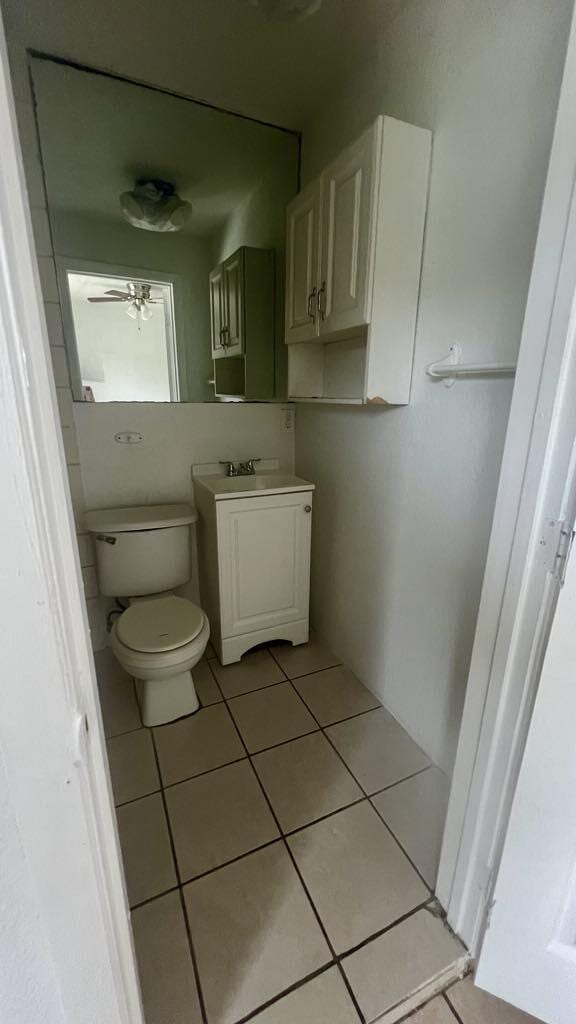 bathroom with tile patterned flooring, ceiling fan, toilet, and vanity