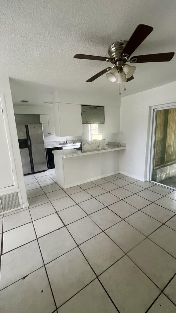 kitchen featuring white cabinetry, ceiling fan, kitchen peninsula, stainless steel fridge, and light tile patterned floors