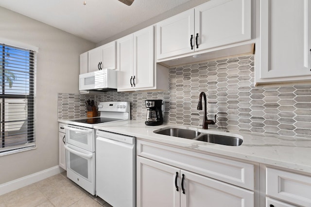 kitchen with white cabinetry, sink, light stone counters, backsplash, and white appliances