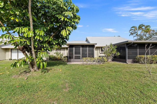 rear view of house featuring a yard and a sunroom