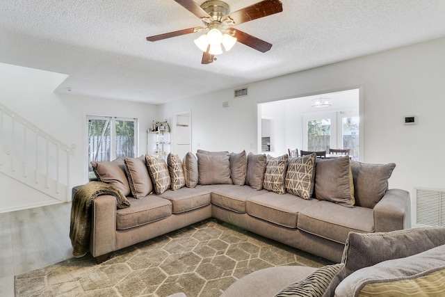 living room with wood-type flooring, a textured ceiling, and ceiling fan