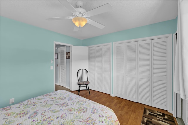 bedroom with hardwood / wood-style flooring, ceiling fan, a textured ceiling, and multiple closets