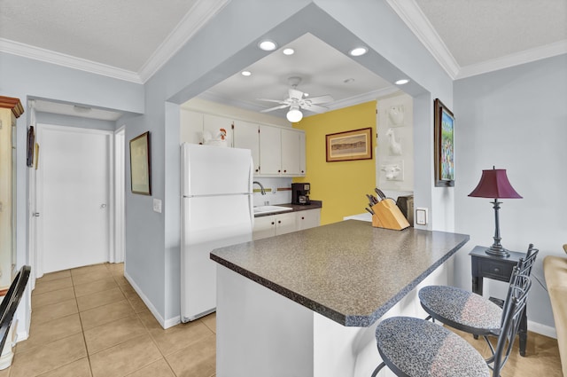 kitchen featuring ornamental molding, ceiling fan, white cabinets, white fridge, and light tile patterned flooring