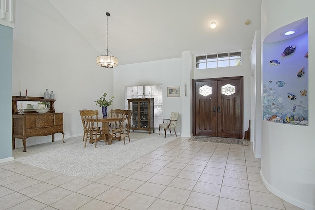 tiled entrance foyer featuring a towering ceiling and a notable chandelier