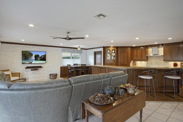 living room with ceiling fan, sink, light tile patterned floors, and ornamental molding