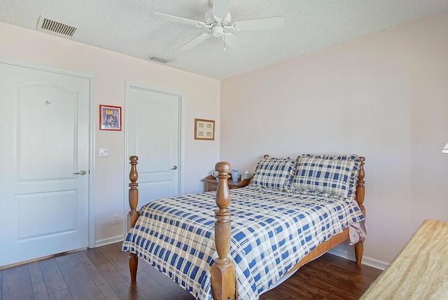 bedroom with a textured ceiling, ceiling fan, and dark wood-type flooring