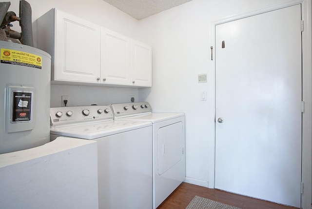 clothes washing area featuring dark wood-type flooring, cabinets, water heater, a textured ceiling, and washer and clothes dryer