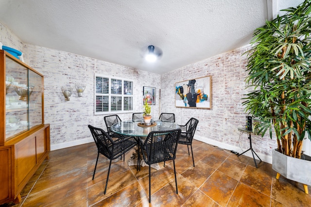 dining area with baseboards, a textured ceiling, and brick wall