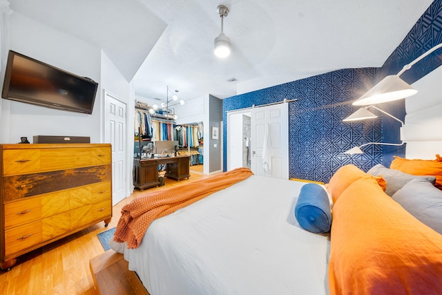 bedroom featuring an accent wall, light wood-style flooring, and a ceiling fan