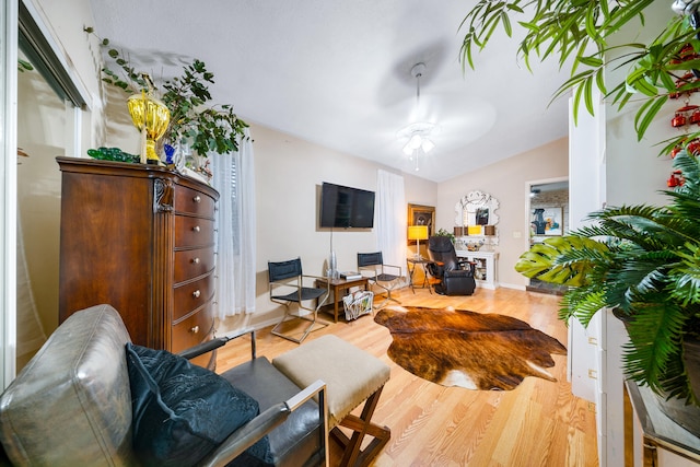 living room featuring a ceiling fan, lofted ceiling, a fireplace, and wood finished floors