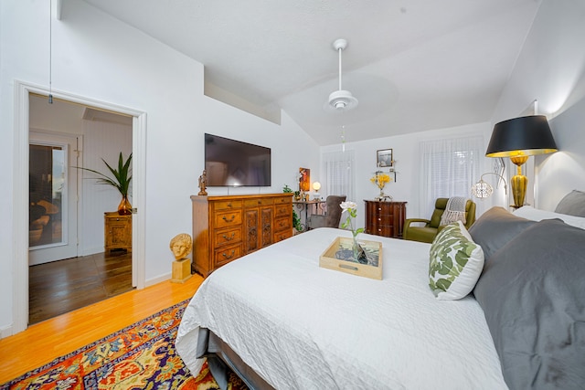 bedroom featuring lofted ceiling, light wood-type flooring, and baseboards