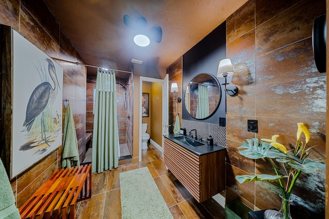 bathroom featuring curtained shower, vanity, tile walls, and toilet