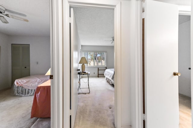 corridor featuring light carpet and a textured ceiling