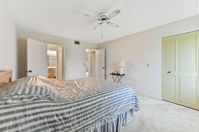 bedroom featuring ceiling fan, a closet, light colored carpet, and a textured ceiling