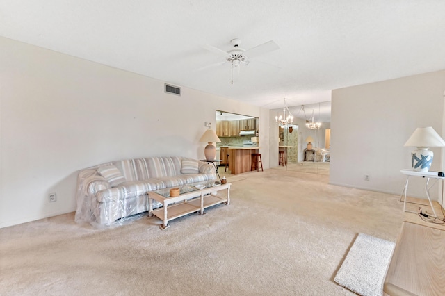 carpeted living room with ceiling fan with notable chandelier