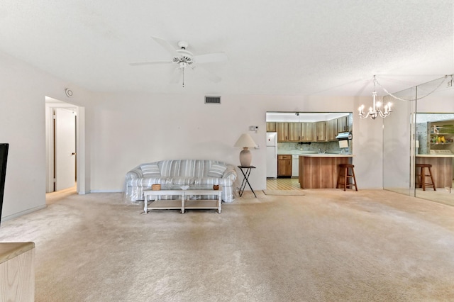 carpeted living room with ceiling fan with notable chandelier and a textured ceiling