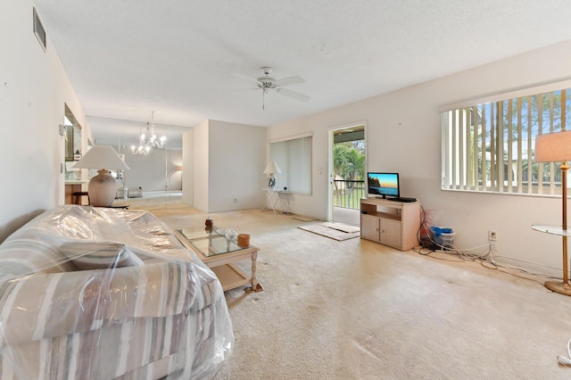 carpeted living room with ceiling fan with notable chandelier