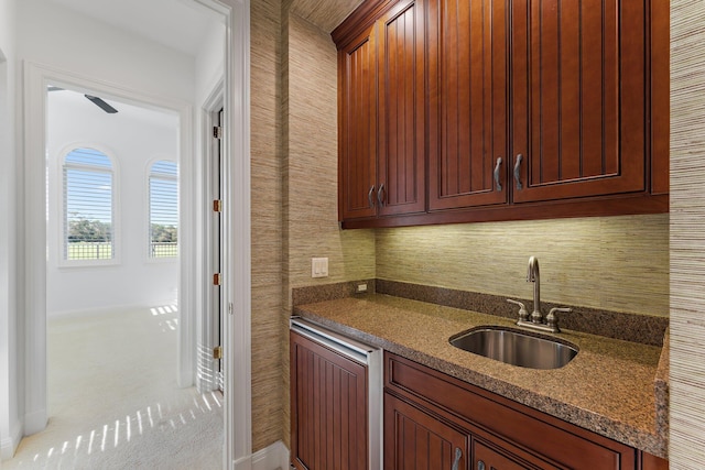 kitchen featuring light colored carpet, sink, and dark stone counters