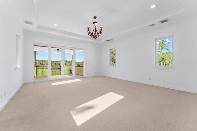 unfurnished room featuring ornamental molding, ceiling fan with notable chandelier, a tray ceiling, and light colored carpet