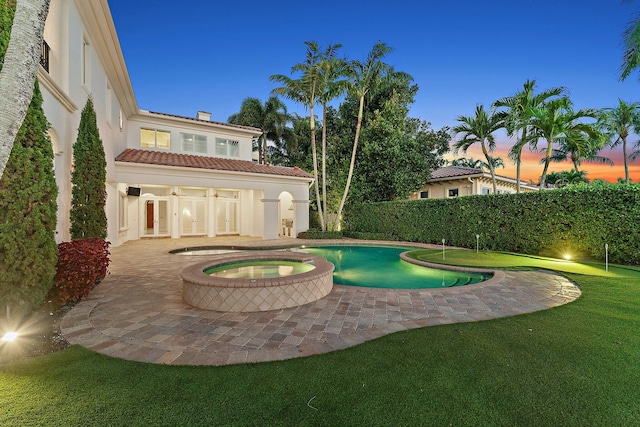 pool at dusk with an in ground hot tub and french doors